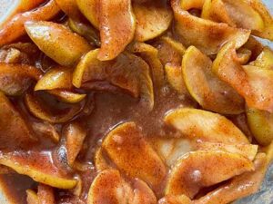 Close-up of apple slices cooking in a caramel-like sauce.