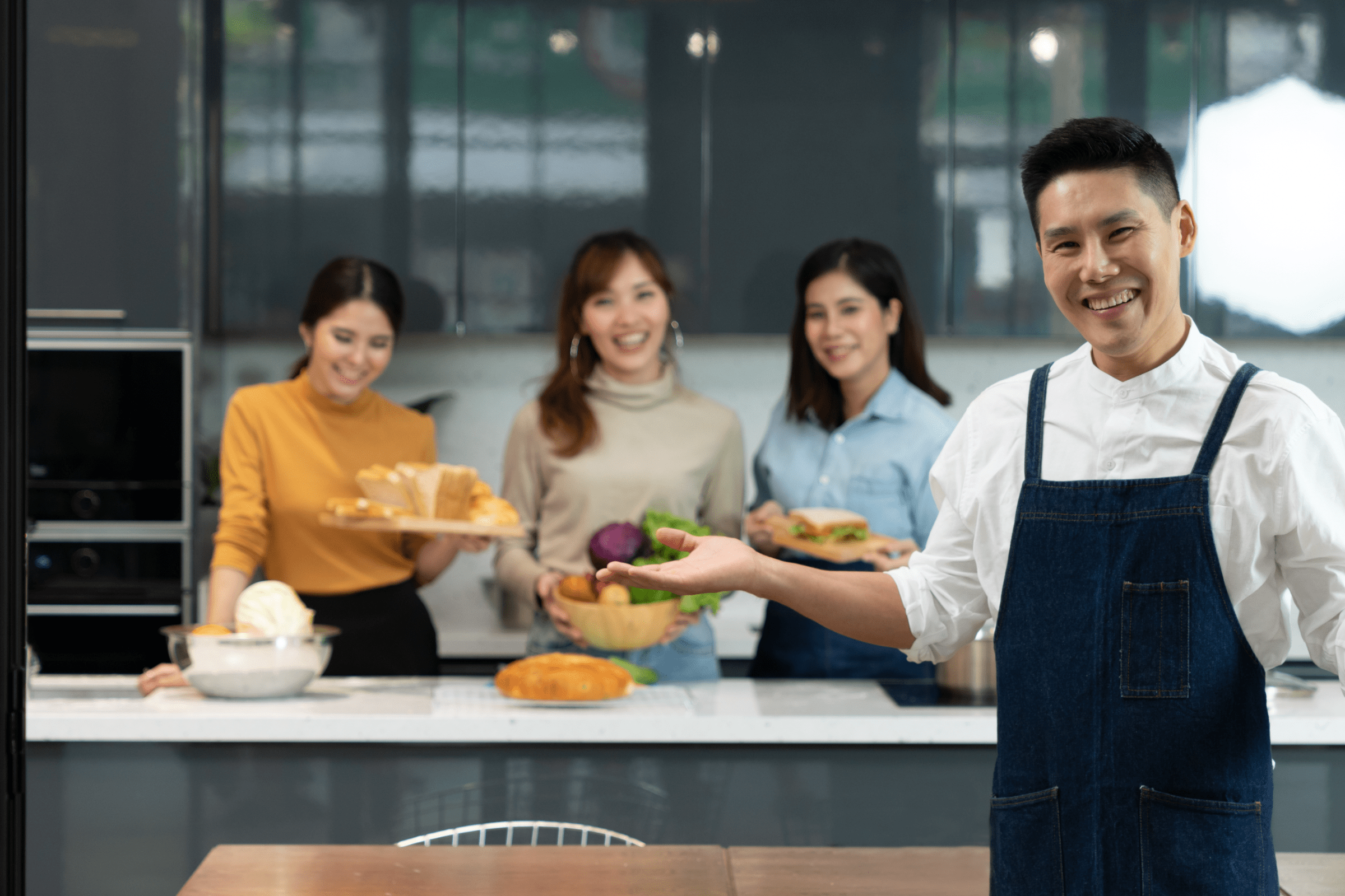 Four people happily presenting homemade dishes in a kitchen.