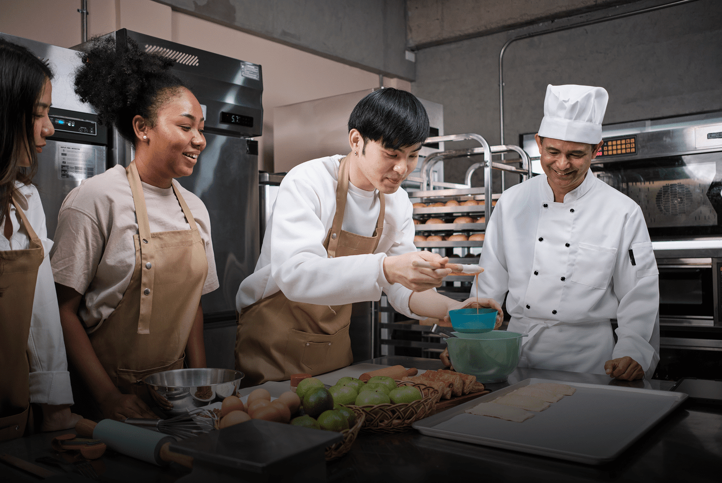 Chef teaching apprentices to prepare food in a kitchen.