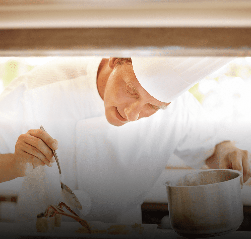 Chef carefully plating a gourmet dish in a professional kitchen.