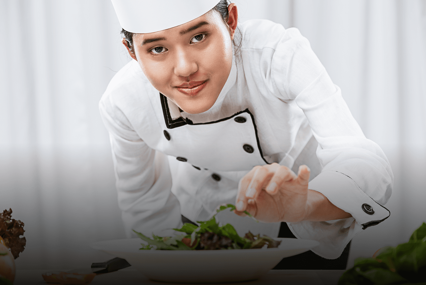 Chef adding final touches to a dish in a professional kitchen.