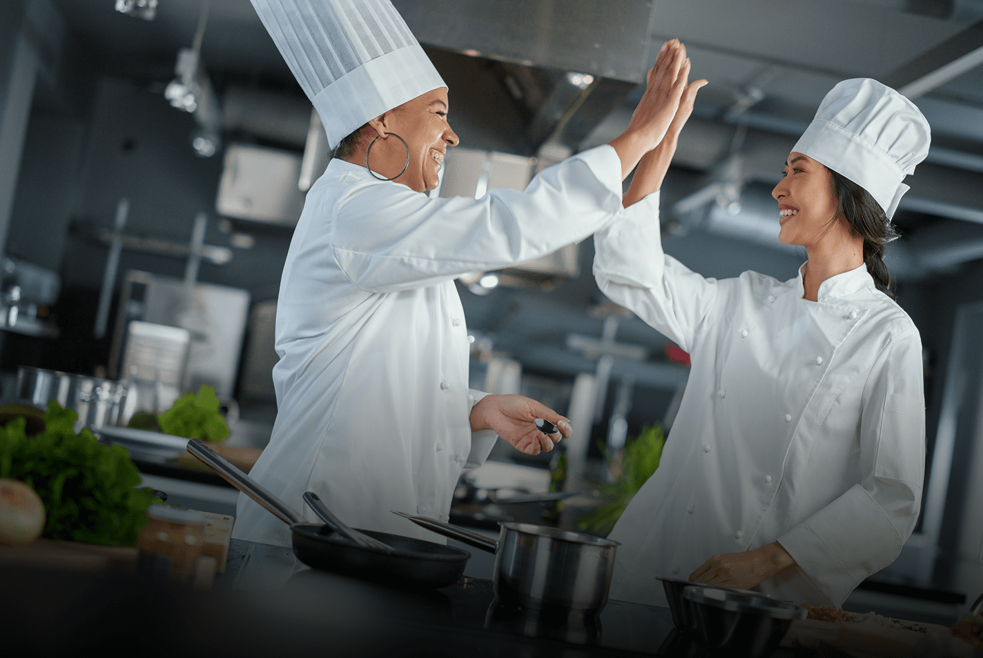 Two chefs high-fiving in a professional kitchen.