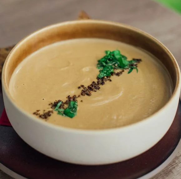Creamy soup garnished with herbs in a white bowl.