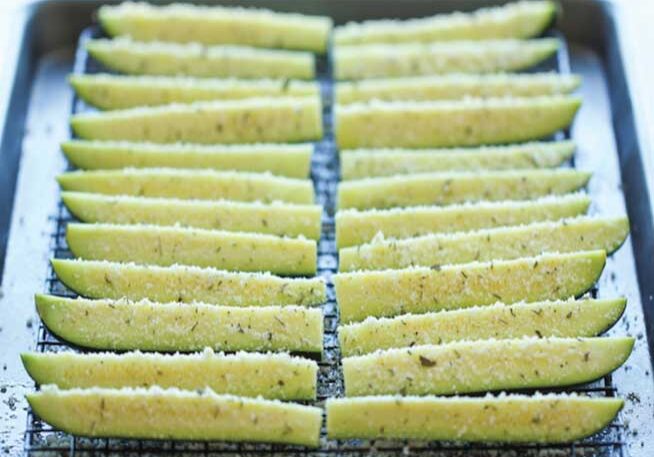 Rows of seasoned potato wedges arranged on a baking tray.
