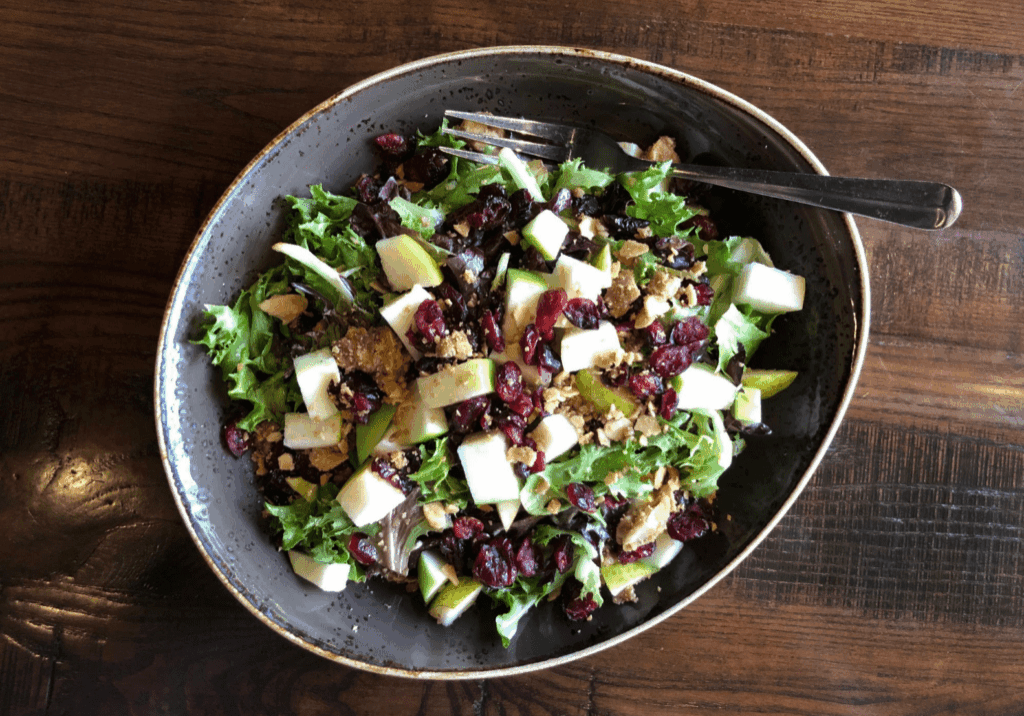 Fresh kale salad with apple cubes, dried cranberries, and sunflower seeds.